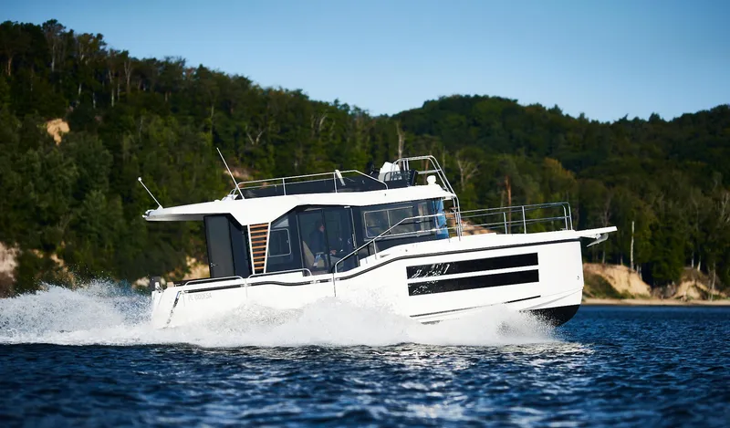 Slide: The Image of 2025 Northman 1050 boat cruising on a scenic lake with forested shoreline. - 15