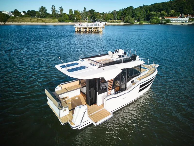 Slide: The Image of 2025 Northman 1050 yacht on serene lake with lush green shoreline. - 2