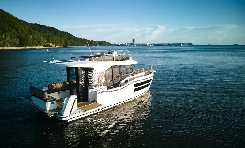 Slide: The Image of 2025 Northman 1050 yacht cruising on a serene lake with lush green shoreline. - 32