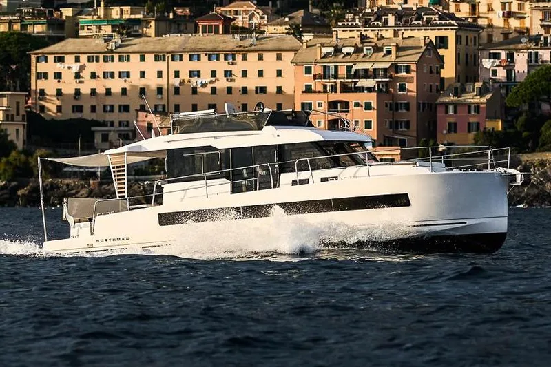 The Image of 2025 Northman 1300 yacht cruising near a scenic coastal town. - 0