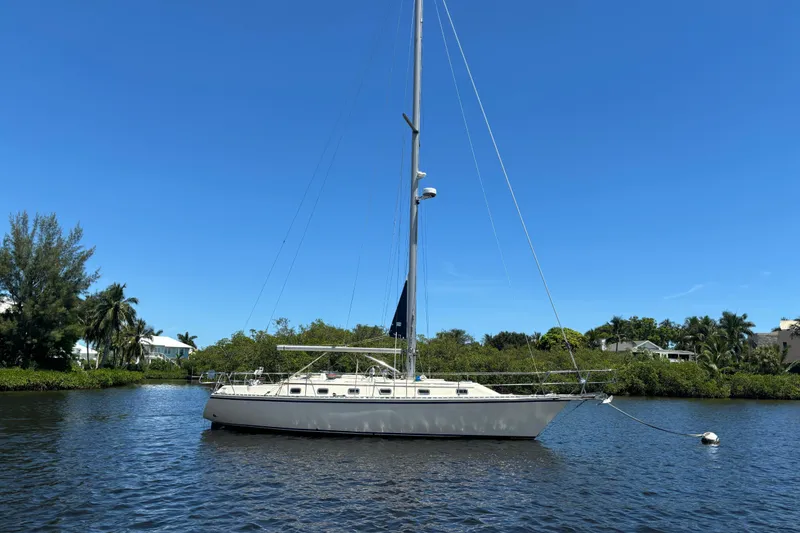 The Image of 1997 Caliber 40LRC sailboat anchored on a calm river under a clear blue sky. - 0