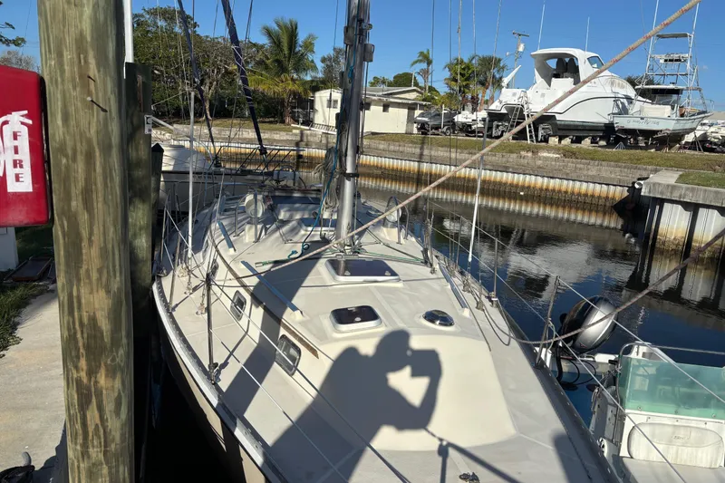 Slide: The Image of 1997 Caliber 40LRC sailboat docked in marina, sunny day, palm trees in background. - 1