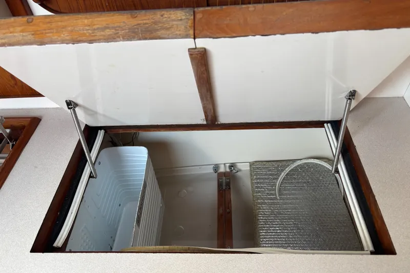 Slide: The Image of Open storage compartment in 1997 Caliber 40LRC boat, featuring metal and wood elements. - 14