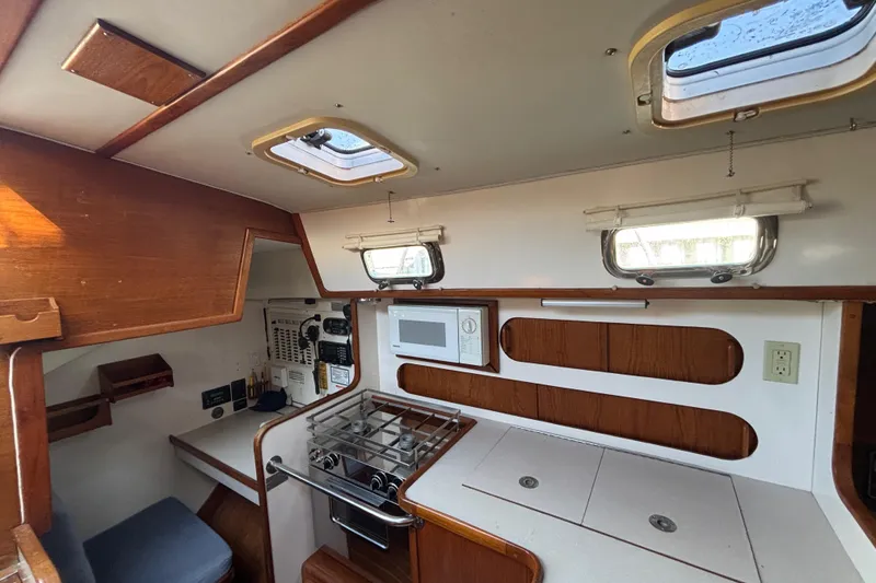 Slide: The Image of Interior of 1997 Caliber 40LRC sailboat galley with stove, microwave, and wooden cabinetry. - 15