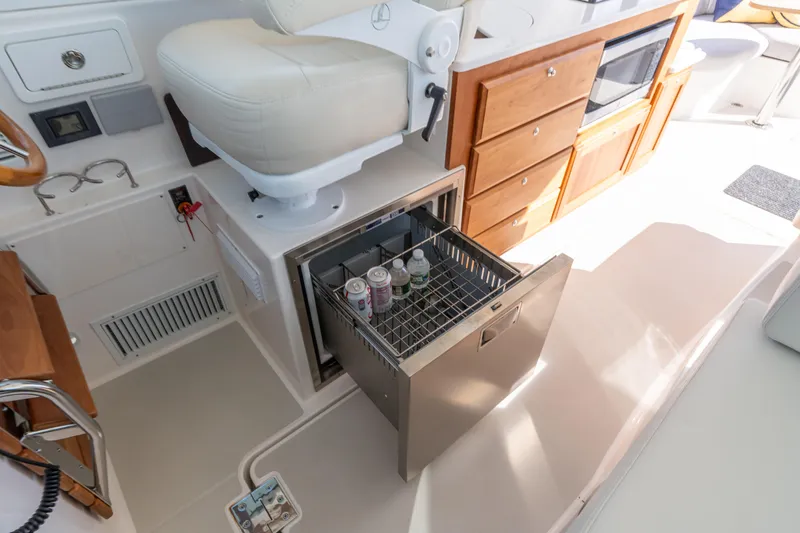 Slide: The Image of 2023 Back Cove 340 interior with open drawer fridge, beverages, and wooden cabinetry. - 19
