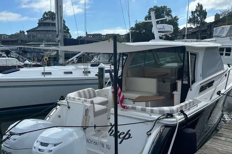 Slide: The Image of 2023 Back Cove 340 boat docked, featuring twin engines and a spacious seating area. - 2