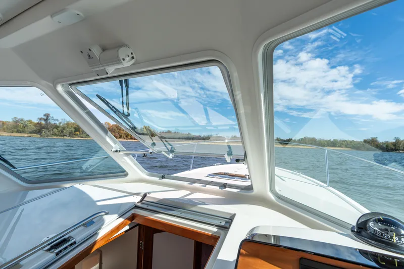 Slide: The Image of Interior view from a 2023 Back Cove 340 boat, showcasing the helm and scenic waterway. - 21