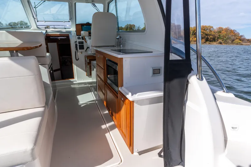 Slide: The Image of Interior of 2023 Back Cove 340 boat with seating, kitchenette, and water view. - 22