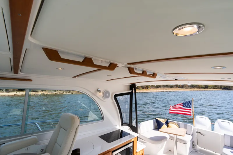 Slide: The Image of 2023 Back Cove 340 boat interior with American flag, featuring elegant seating and water view. - 28
