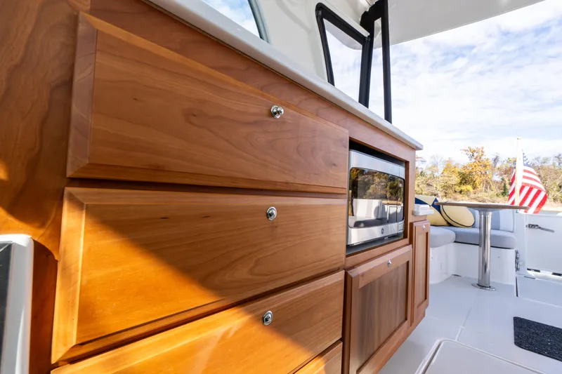 Slide: The Image of 2023 Back Cove 340 interior with wooden cabinetry and microwave, showcasing luxury boat design. - 32