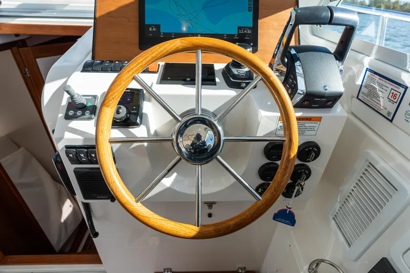 Slide: The Image of 2023 Back Cove 340 helm with wooden steering wheel and modern navigation controls. - 37