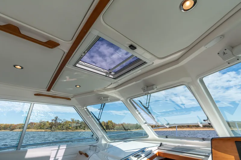 Slide: The Image of Interior view of 2023 Back Cove 340 boat with skylight and scenic water backdrop. - 39