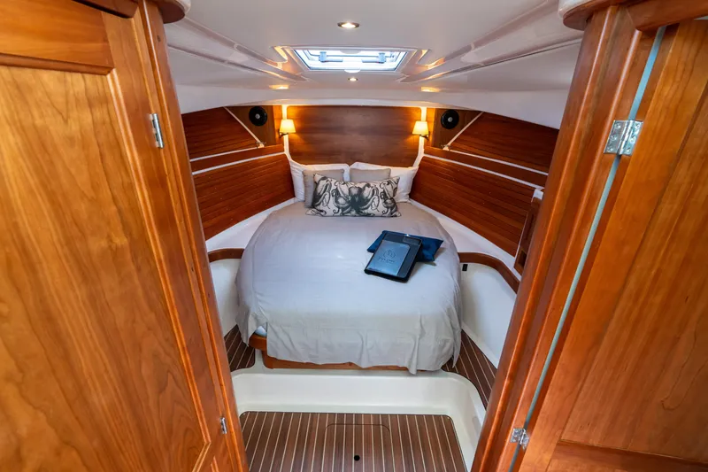 Slide: The Image of 2023 Back Cove 340 cabin interior with cozy bed and wooden accents. - 49