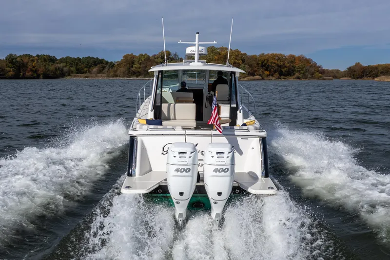 Slide: The Image of 2023 Back Cove 340 boat cruising on a lake with twin outboard engines. - 5