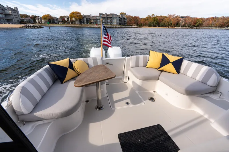 Slide: The Image of 2023 Back Cove 340 boat interior with striped seating, cushions, and wooden table. - 6