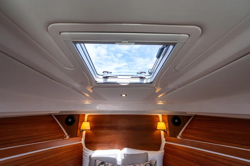 Slide: The Image of 2023 Back Cove 340 cabin interior with skylight, wooden paneling, and cozy lighting. - 61
