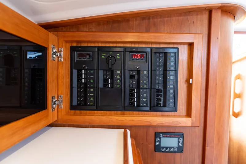 Slide: The Image of Electrical panel inside 2023 Back Cove 340 boat, featuring wooden cabinetry and control switches. - 64