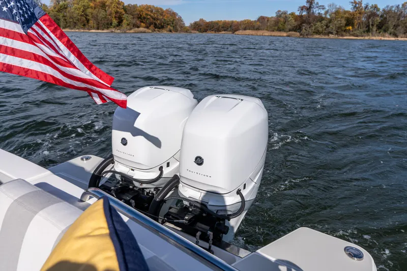 Slide: The Image of 2023 Back Cove 340 boat with dual outboard engines and American flag on a lake. - 68