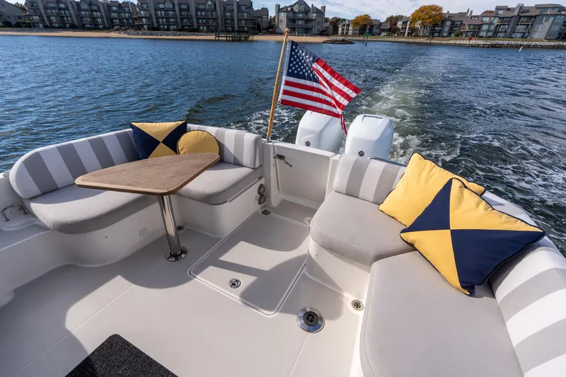 Slide: The Image of 2023 Back Cove 340 boat interior with striped seating, cushions, and American flag on water. - 7