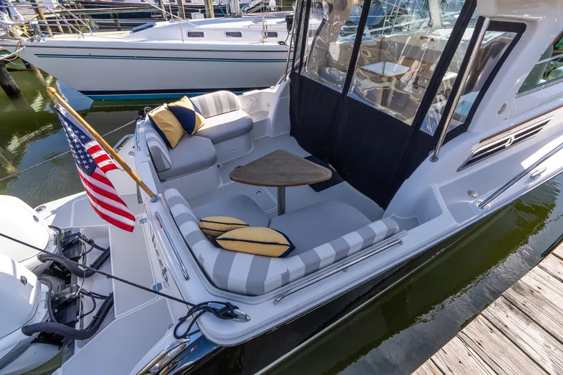 Slide: The Image of 2023 Back Cove 340 boat with cozy seating and American flag at dock. - 74