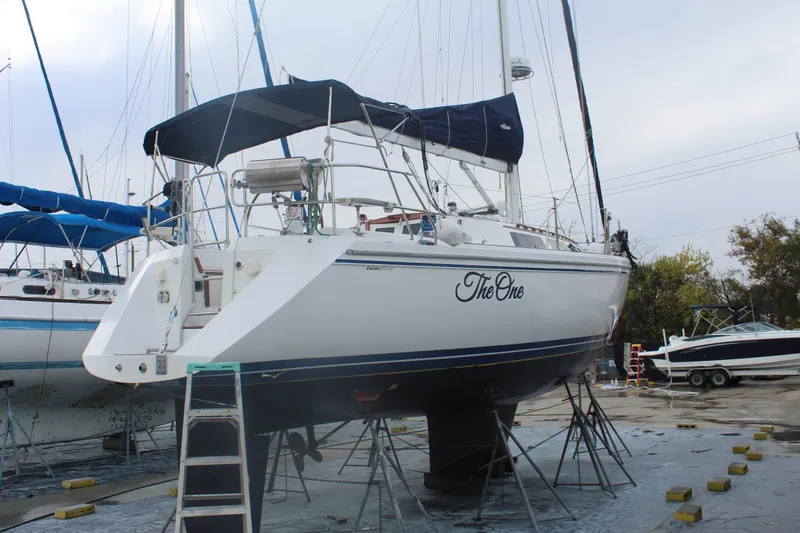 Slide: The Image of Catalina 42 sailboat from 1990 on dry dock, named "The One," with blue canopy. - 54