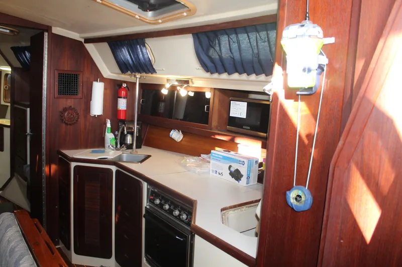 Slide: The Image of Interior of a 1990 Catalina 42 sailboat kitchen with wood cabinetry and appliances. - 11