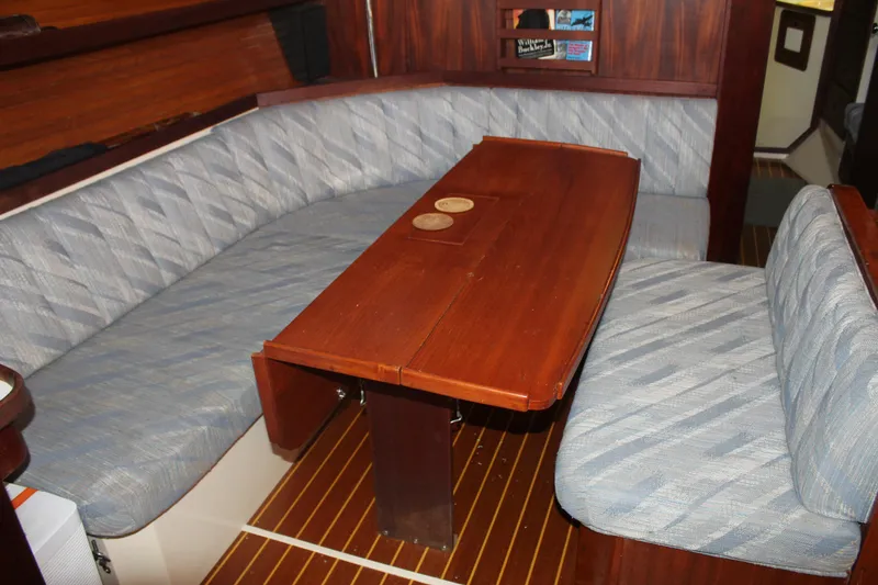 Slide: The Image of Interior of a 1990 Catalina 42 sailboat with wooden table and cushioned seating. - 10