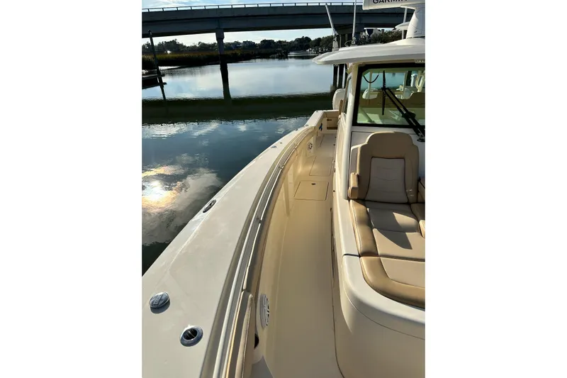 Slide: The Image of 2019 Scout 380 LXF boat on calm water near a bridge, showcasing luxury seating. - 10