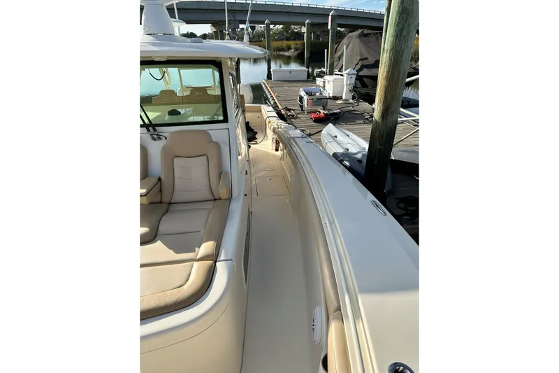 Slide: The Image of 2019 Scout 380 LXF boat docked, featuring beige seating and sleek design. - 11
