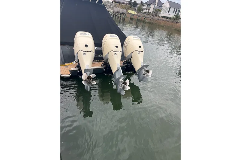 Slide: The Image of 2019 Scout 380 LXF boat with triple outboard engines docked in calm waters. - 16