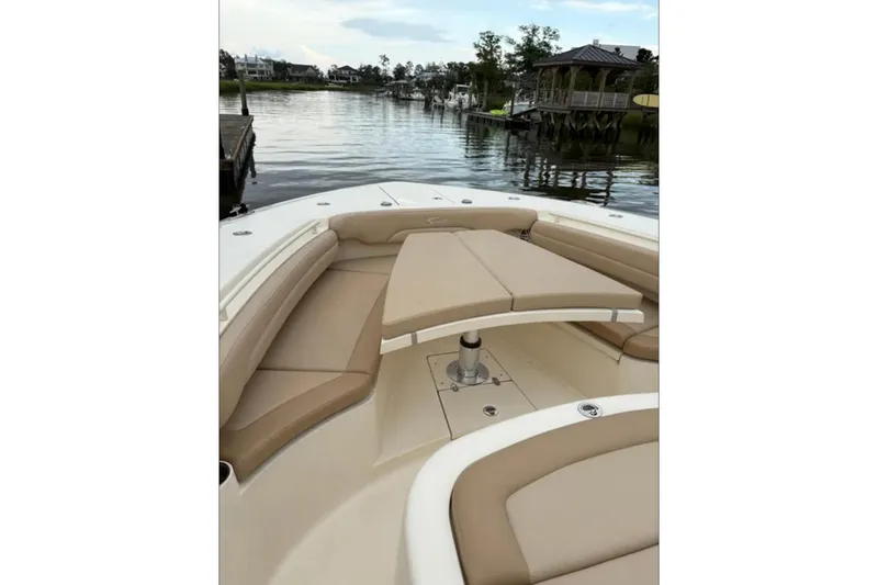 Slide: The Image of 2019 Scout 380 LXF boat with tan seating, docked by a serene waterfront. - 19
