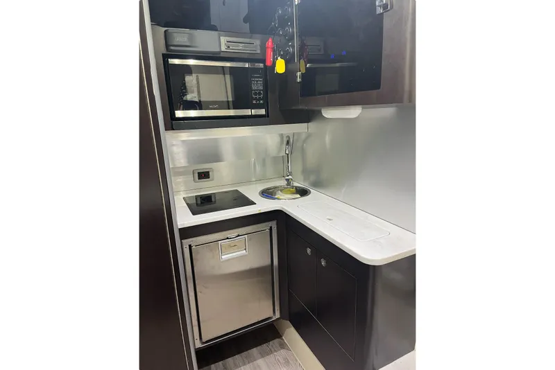 Slide: The Image of Compact kitchen area in a 2019 Scout 380 LXF boat, featuring modern appliances and sleek design. - 25