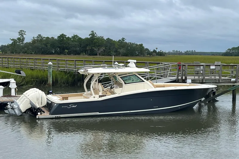 Slide: The Image of 2019 Scout 380 LXF boat docked by a wooden pier on a cloudy day. - 27