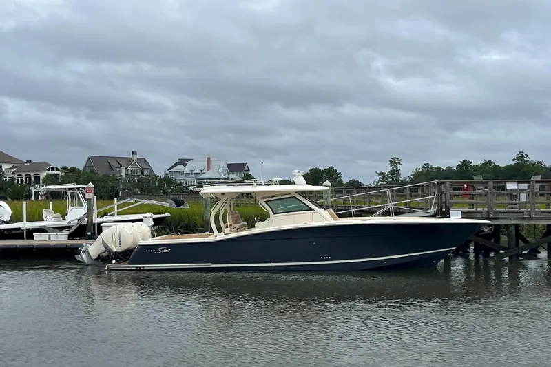Slide: The Image of 2019 Scout 380 LXF boat docked by a wooden pier under cloudy skies. - 28