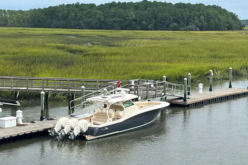 Slide: The Image of 2019 Scout 380 LXF boat docked by a scenic marshland. - 29