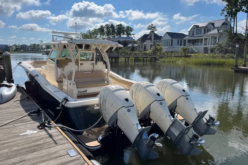 Slide: The Image of 2019 Scout 380 LXF boat docked by waterfront homes under a blue sky. - 3