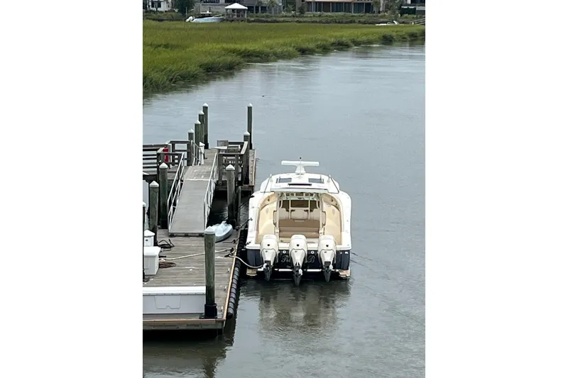 Slide: The Image of 2019 Scout 380 LXF boat docked on calm waterway. - 30