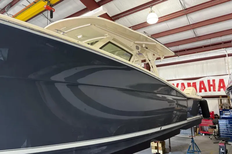 Slide: The Image of 2019 Scout 380 LXF boat in a workshop, side view with Yamaha banner. - 32