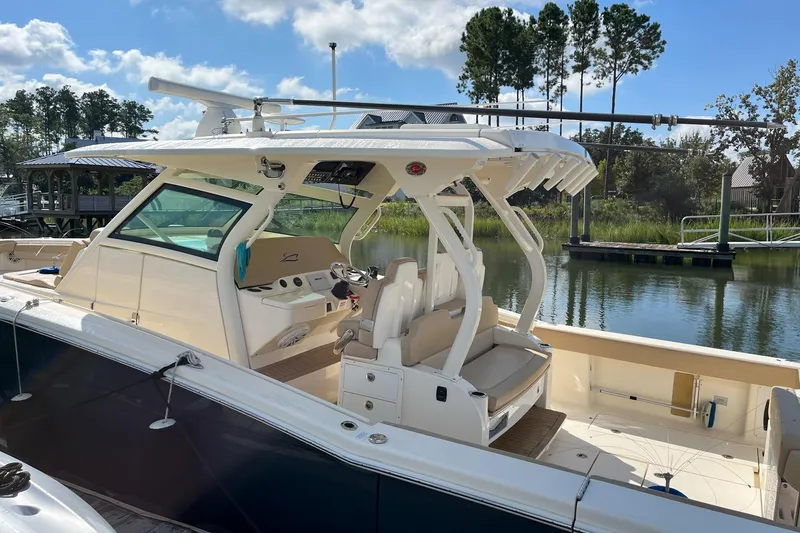 Slide: The Image of 2019 Scout 380 LXF boat docked by a serene waterfront with trees in the background. - 4