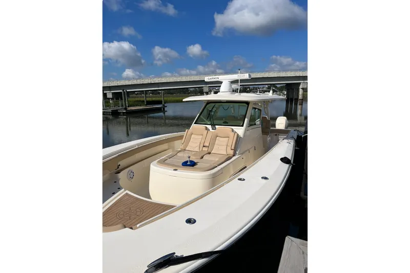 Slide: The Image of 2019 Scout 380 LXF boat docked under a clear blue sky. - 6
