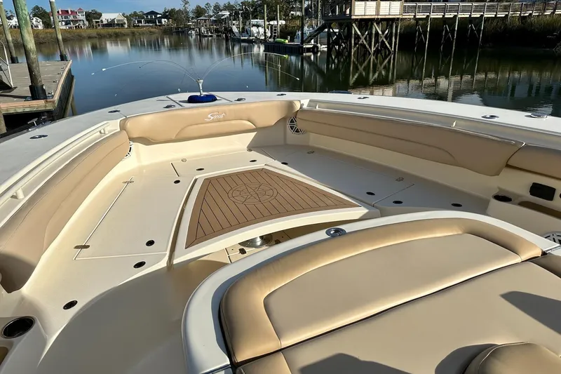 Slide: The Image of 2019 Scout 380 LXF boat interior with beige seating and wooden deck, docked by calm water. - 8