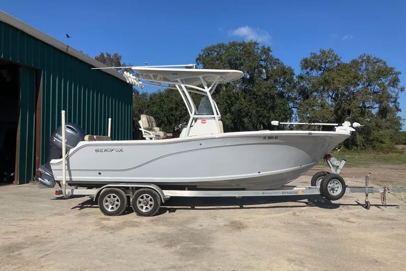 The Image of 2018 Sea Fox 226 Commander boat on trailer, parked outdoors near a green building. - 0
