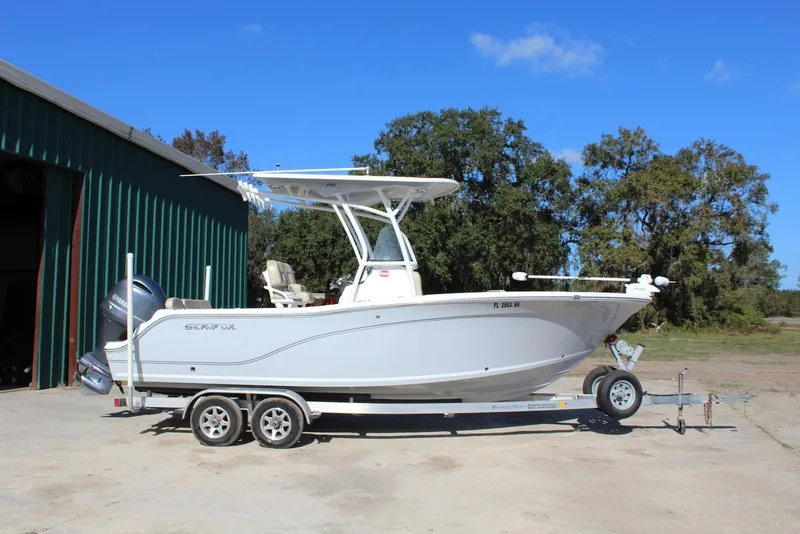 Slide: The Image of 2018 Sea Fox 226 Commander boat on trailer, parked outdoors near a green building. - 4