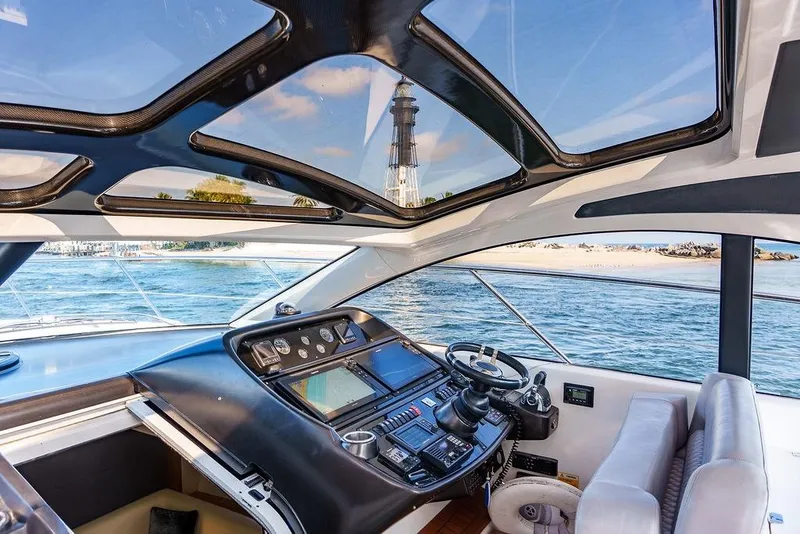 Slide: The Image of Cockpit view of 2013 Sunseeker Portafino yacht, featuring navigation controls and waterfront scenery. - 23