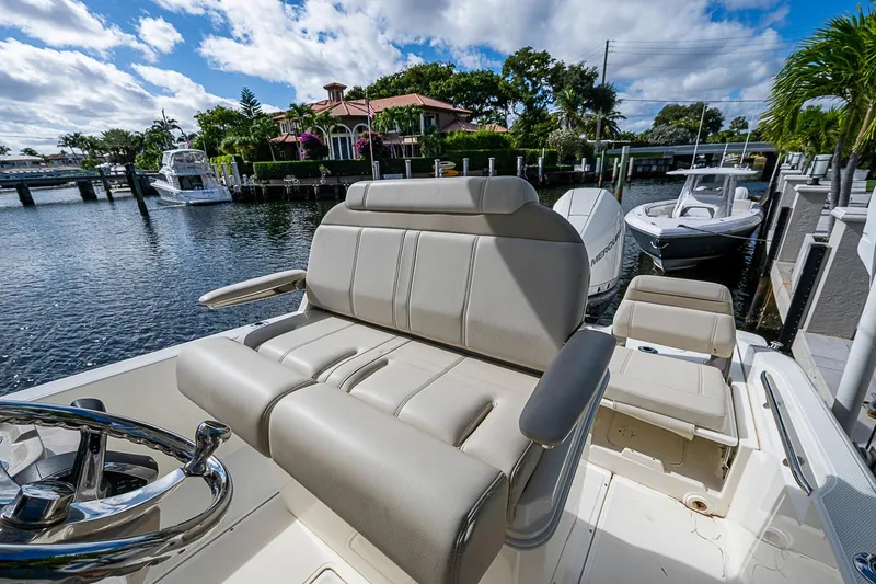 Slide: The Image of 2023 Boston Whaler 250 Dauntless boat interior with seating, docked by waterfront homes. - 10