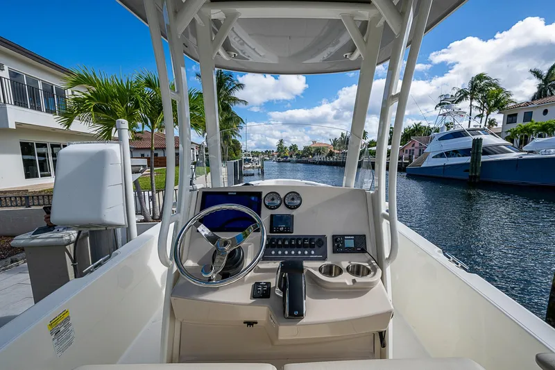 Slide: The Image of 2023 Boston Whaler 250 Dauntless boat helm with waterfront view, palm trees, and luxury yachts. - 16