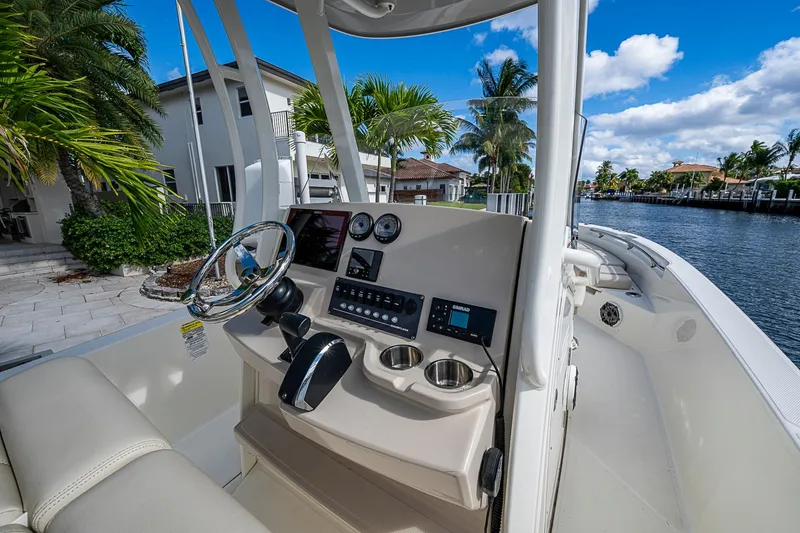 Slide: The Image of 2023 Boston Whaler 250 Dauntless boat interior with steering console, near waterfront homes. - 17