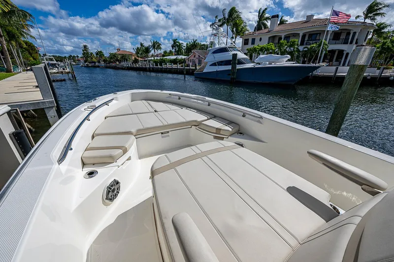 Slide: The Image of 2023 Boston Whaler 250 Dauntless boat interior with luxurious seating, docked by waterfront homes. - 2