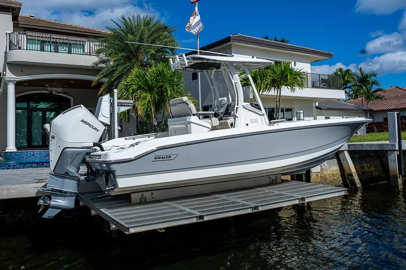 Slide: The Image of 2023 Boston Whaler 250 Dauntless boat docked by a waterfront home. - 25