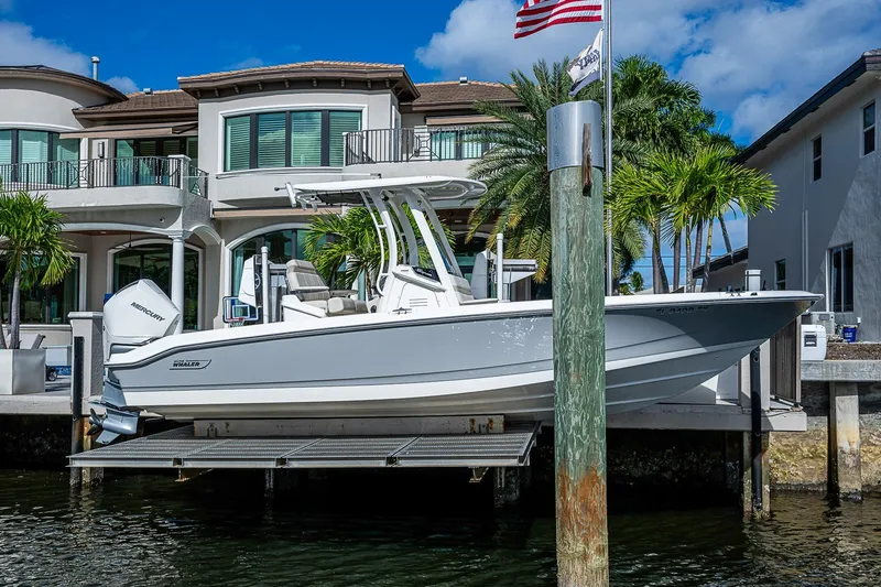 Slide: The Image of 2023 Boston Whaler 250 Dauntless boat docked by luxury waterfront homes. - 27